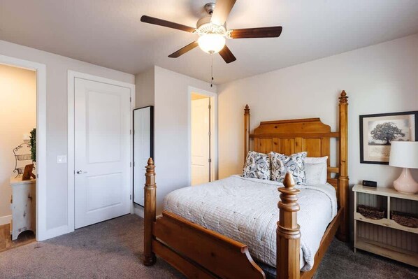 A bedroom with a wooden bed, a ceiling fan, and a bedside table with a lamp.
