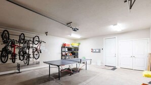 Une pièce avec une table de ping-pong, des vélos et une porte blanche.