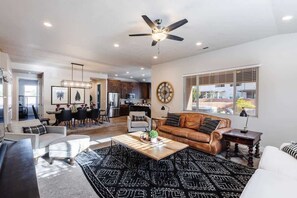 A spacious living room with a ceiling fan, a coffee table, and a large rug.