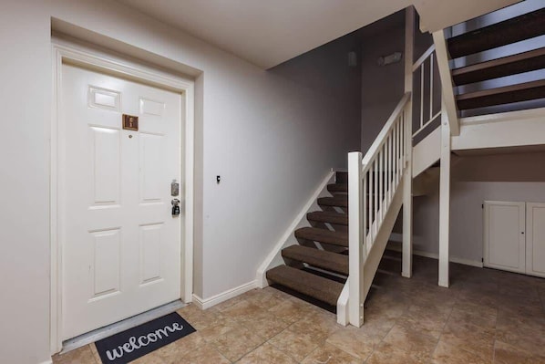 A staircase with a white handrail and carpeted steps leading to a landing.