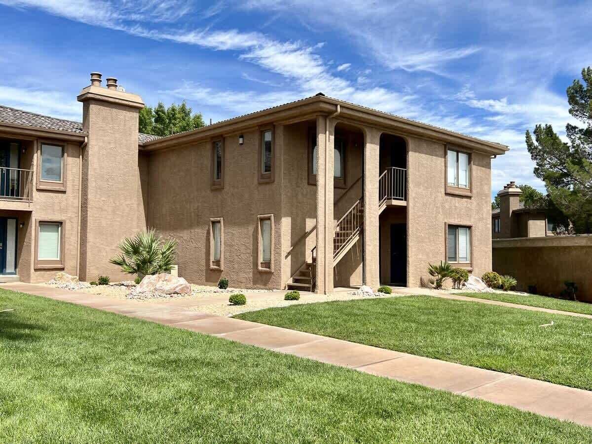 A two-story residential building with a central staircase, a front entrance, and a well-maintained lawn.