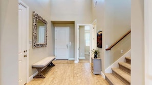 A hallway with a bench, a door, a mirror, and a staircase.