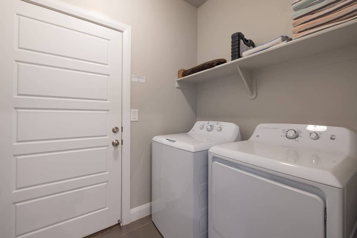 A laundry room with two washing machines and a white door.