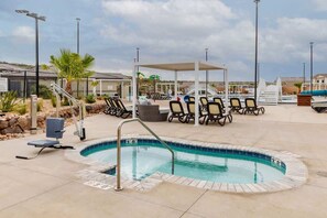 Une piscine avec des chaises longues et un espace salon abrité.
