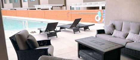 Un área junto a la piscina con sillones de descanso, un sofá y una mesa de centro.