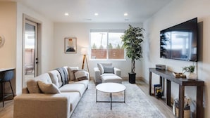 A modern living room with a sofa, armchair, coffee table, and a TV mounted on the wall. - Lava Flow @ Heritage Point - Santa Clara (Santa Clara)