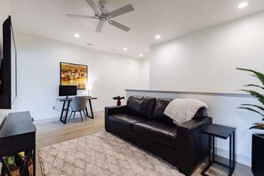 A modern living room with a leather sofa, a flat-screen TV, a ceiling fan, and a painting on the wall. - Lava Flow @ Heritage Point - Santa Clara (Santa Clara)