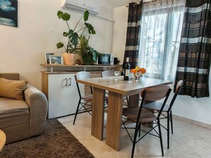 A dining area with a wooden table, chairs, a potted plant, a microwave, and a bottle of wine. - Holiday apartment with terrace (Medulin)