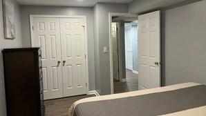Een slaapkamer met een bed, een kledingkast en een deur naar een andere kamer.