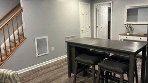 Een eethoek met een tafel en twee stoelen, een trap en een deur naar een andere kamer.