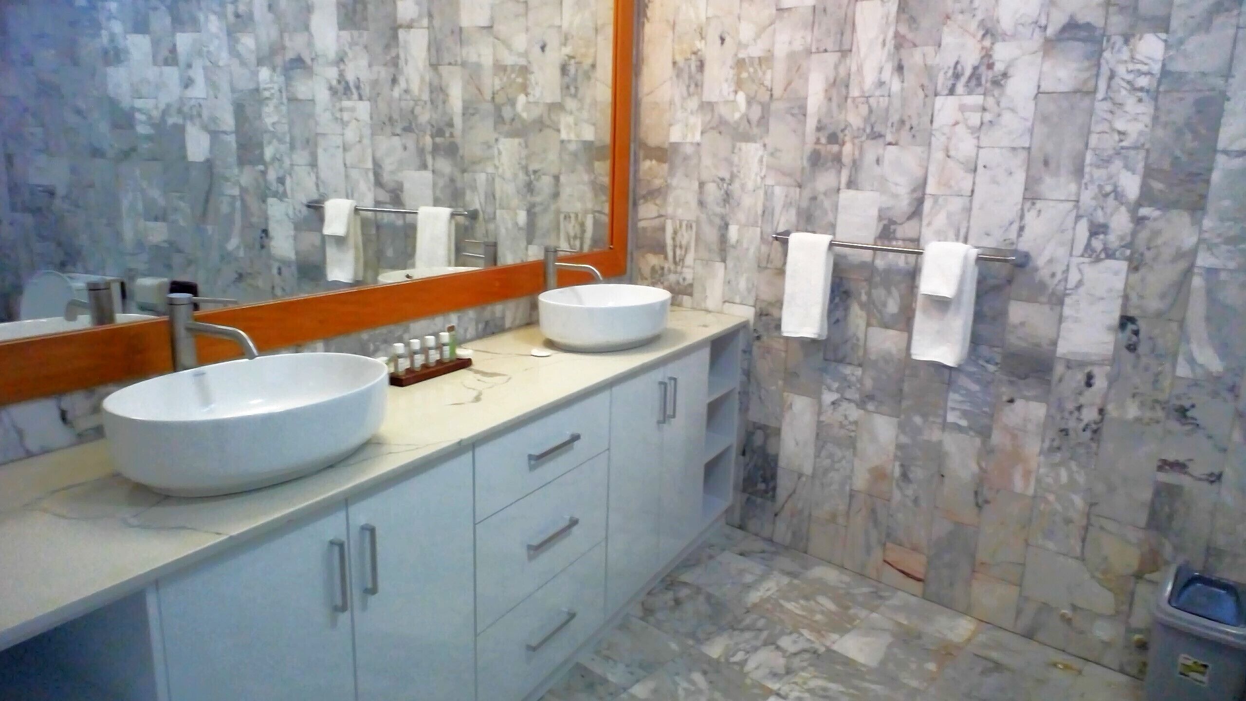 A bathroom with two white sinks, a mirror, and a marble-patterned wall.