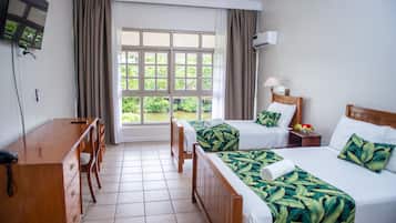 Een hotelkamer met twee bedden, een bureau, een stoel, een televisie en een raam met gordijnen.