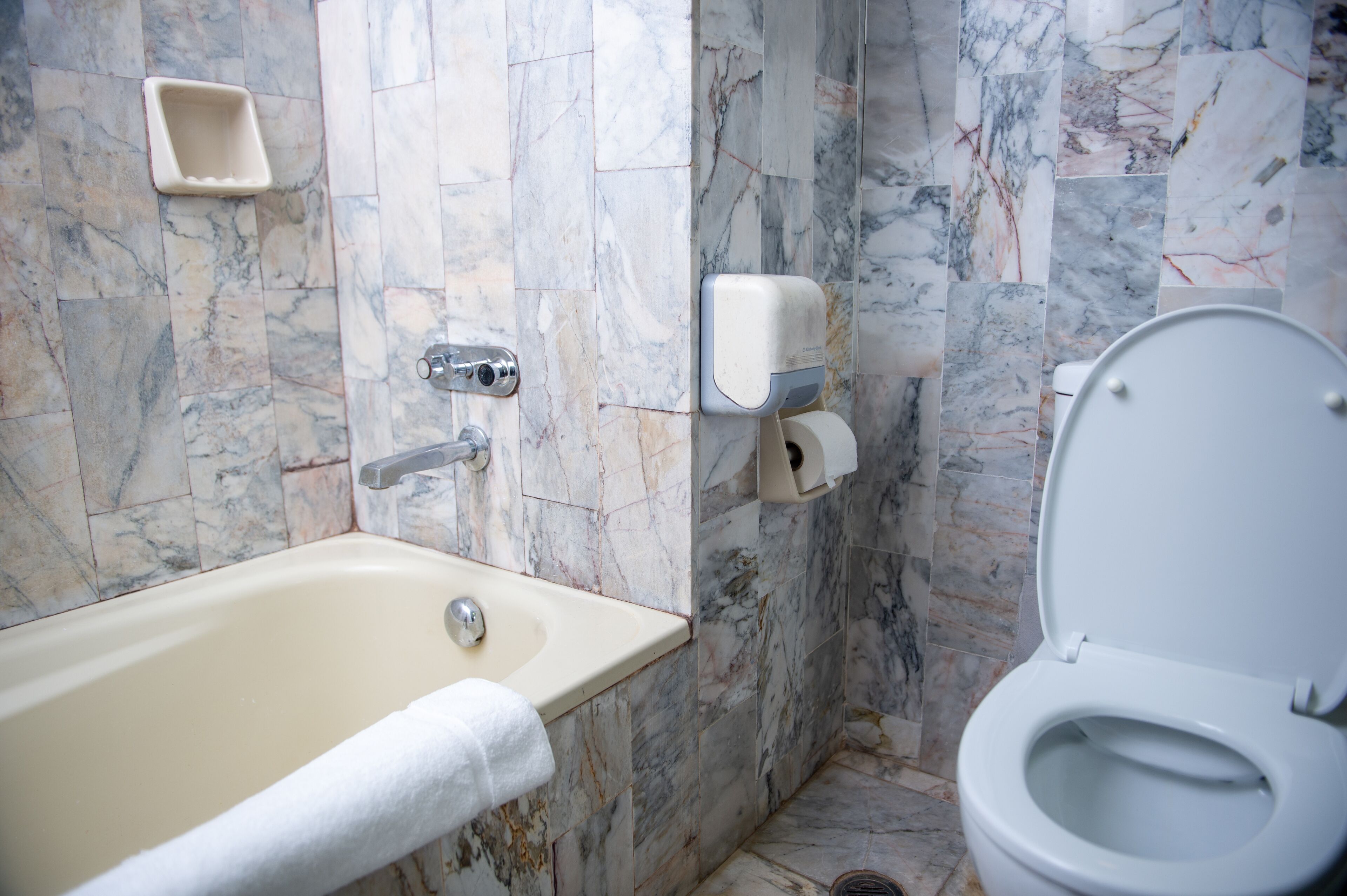 Un baño con bañera, inodoro y paredes de mármol.