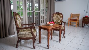 A room with two ornate wooden chairs, a small wooden table with a flower vase, and a plain wooden chair. - Yatu Lau Lagoon Resort  (Pacific Harbour)