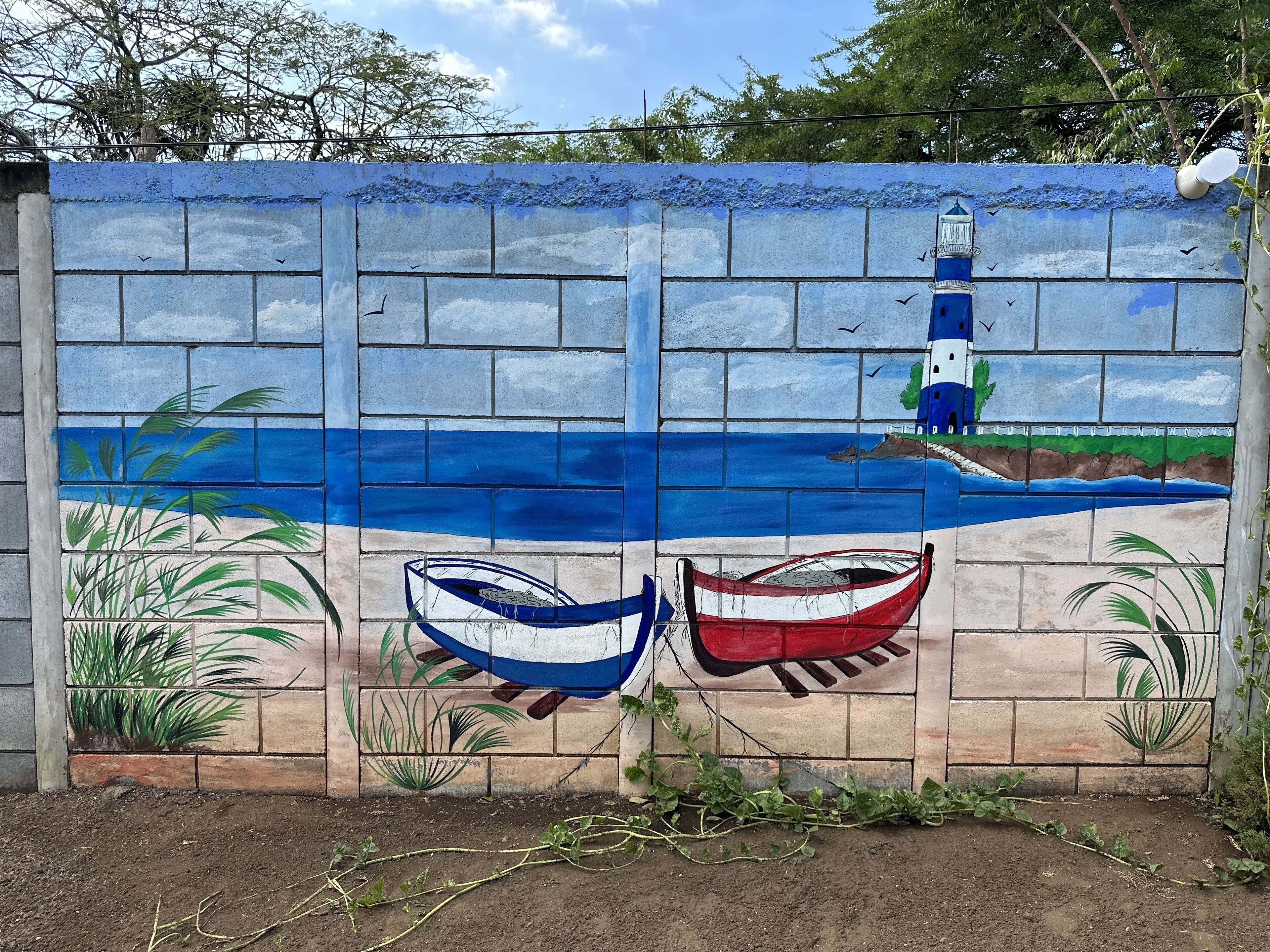 A mural of a beach scene with two boats and a lighthouse.