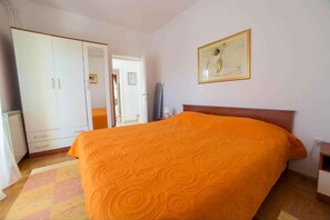 Une chambre à coucher comprenant un lit, une armoire, une porte et un tableau accroché au mur.