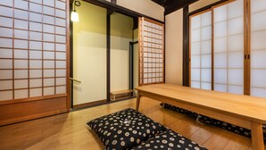 A traditional Japanese room with tatami flooring, a low wooden table, and shoji screens. - Shiki Homes Machiya Mei (Kyoto)