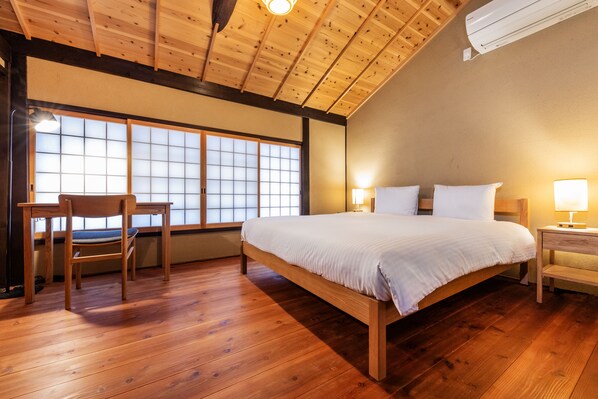 A bedroom with a wooden bed, a chair, a nightstand, and a window with a view.