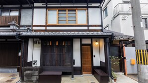 A traditional Japanese building with a wooden entrance, a small porch, and a potted plant. - Shiki Homes Machiya Mei (Kyoto)