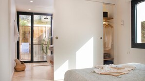 Un dormitorio con cama, armario y puerta corredera que da a un espacio exterior con valla de bambú.