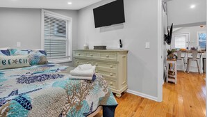 A bedroom with a bed, a dresser, a TV, and a bathroom visible through an open door. - Professionally Managed | 3 Blocks to Beach (Seaside Heights)