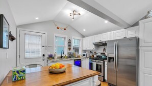 A modern kitchen with white cabinetry, a stainless steel refrigerator, and a wooden island with a bowl of fruit. - Professionally Managed | 3 Blocks to Beach (Seaside Heights)