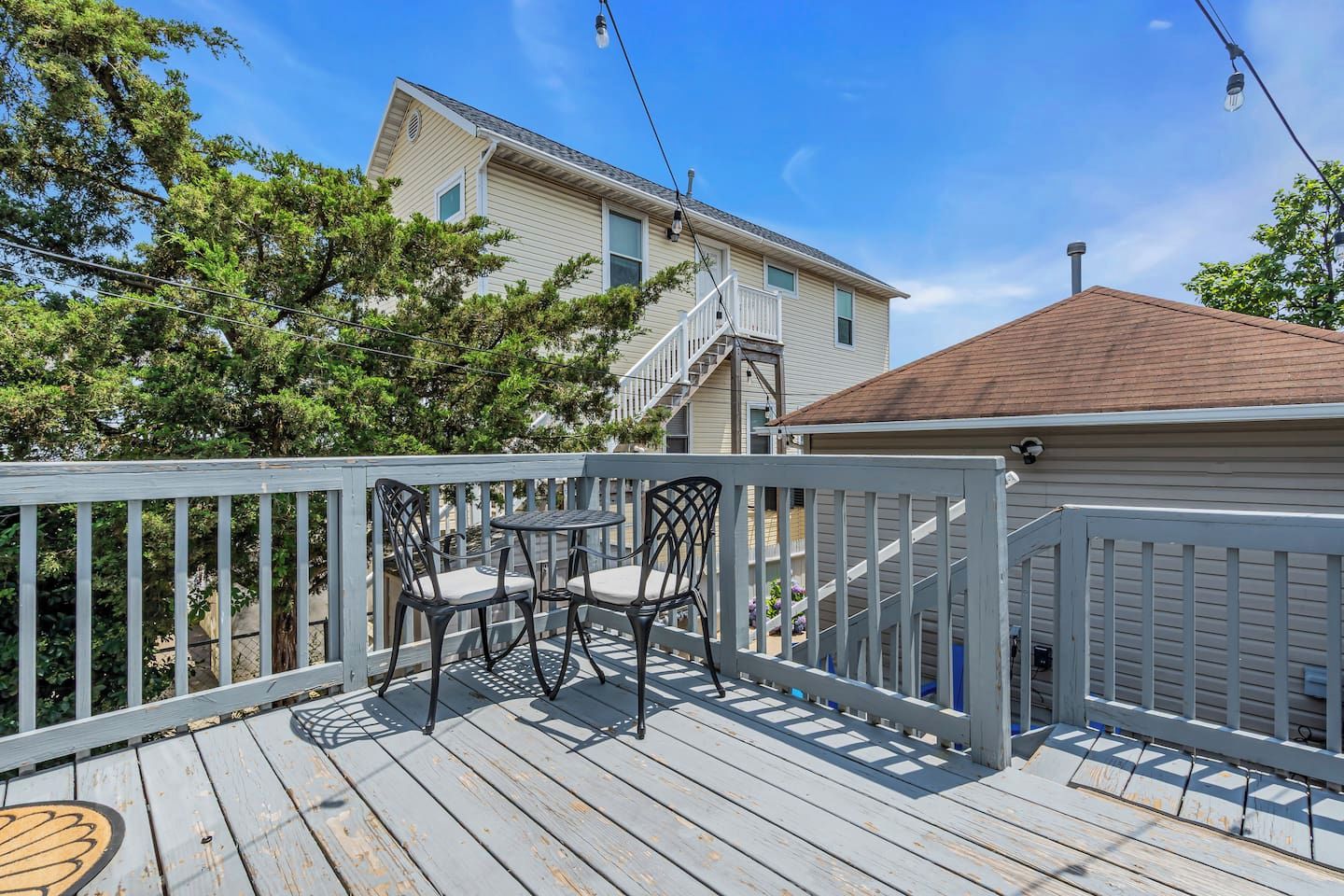 Une terrasse en bois avec une table et des chaises, une rambarde et une maison en arrière-plan.