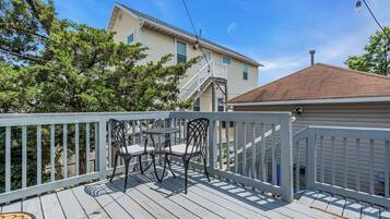 Une terrasse en bois avec une table et des chaises, une rambarde et une maison en arrière-plan.