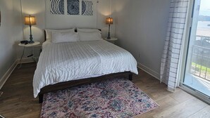 A bedroom with a bed, a ceiling fan, two bedside tables with lamps, a patterned rug, and a large window with curtains. -  Perfectly located Lake Hamilton lake front condo. 5 miles to Oaklawn Race Track (Lake Hamilton)