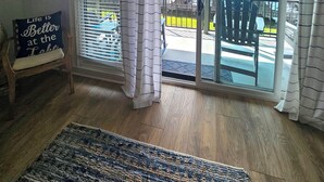 A room with a view of a body of water, a wooden chair with a cushion, and a rug on the floor. -  Perfectly located Lake Hamilton lake front condo. 5 miles to Oaklawn Race Track (Lake Hamilton)