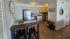 A kitchen with a wooden table, two black stools, a stainless steel refrigerator, and a tiled backsplash. -  Perfectly located Lake Hamilton lake front condo. 5 miles to Oaklawn Race Track (Lake Hamilton)