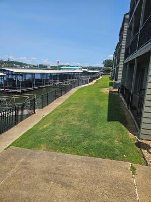 A waterfront property with a grassy area, a dock, and a building with balconies.