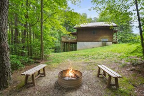 A rustic cabin with a fire pit and two benches in a forest setting. - Moonlight Ridge Cabin | Hocking Hills, 200 Acres (South Bloomingville)