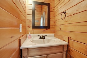 A wooden cabin bathroom with a white sink, a mirror, and a towel rack.