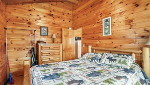 A wooden cabin bedroom with a bed, dresser, and a framed picture on the wall. - Sunset Ridge Cabin | 200 Acres, Pets, Hot Tub (South Bloomingville)