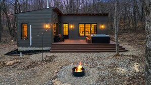 Een moderne chalet met vuurkorf, zitplaatsen buiten en een hottub.