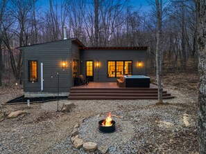 Een moderne chalet met vuurkorf, zitplaatsen buiten en een hottub.