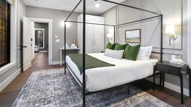 Een hemelbed met een groen plaid, een nachtkastje met zakdoosje en een nachtlampje.