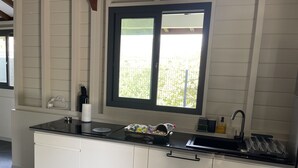 Una cucina moderna con un piano di lavoro nero, mobili bianchi, una finestra con vista sul verde e un lavello con un rubinetto.