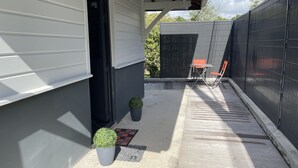 Un'area esterna coperta con patio, un tavolino e sedie, e piante in vaso.