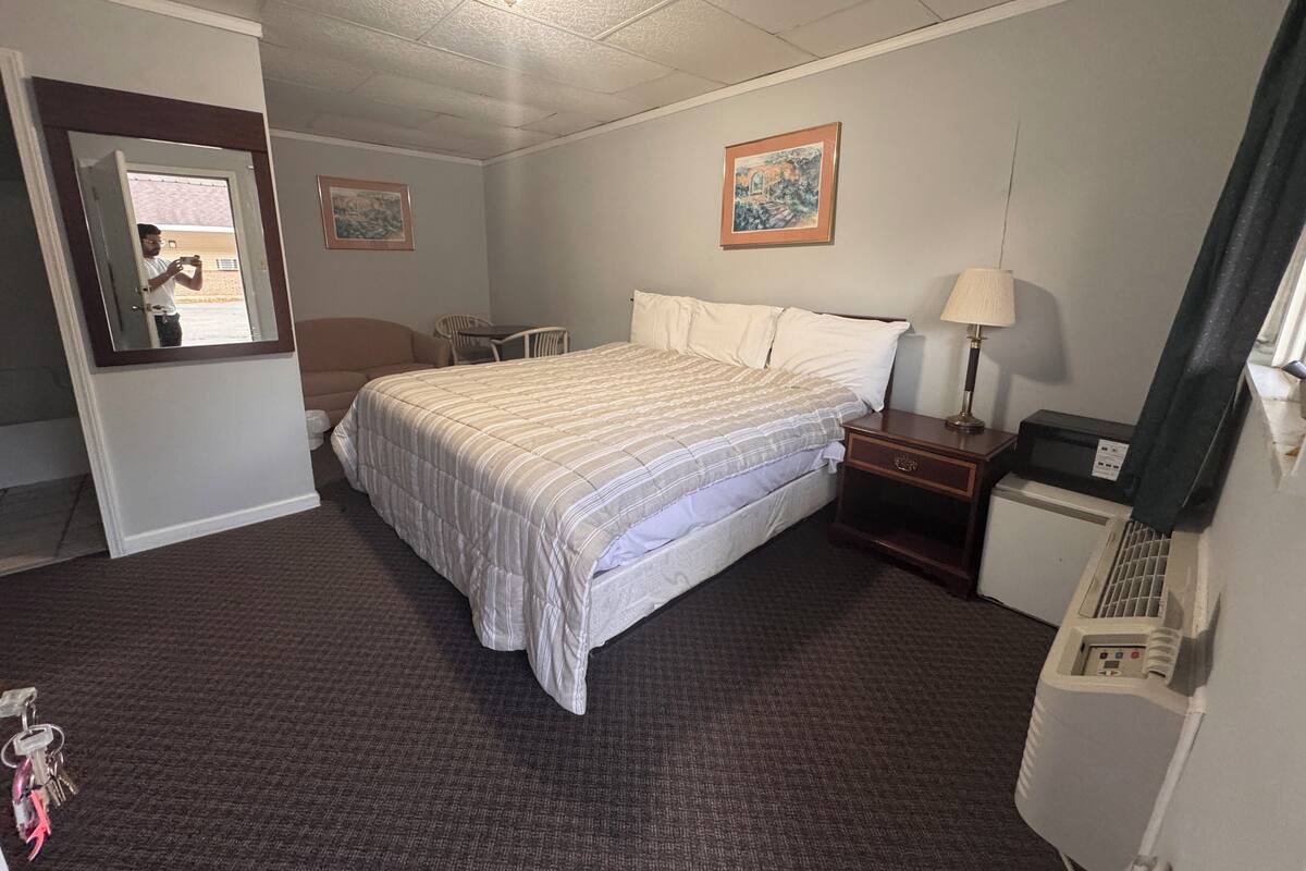 Una habitación de hotel con una cama, un escritorio, una silla, un espejo y una ventana.