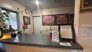 A hotel reception area with a counter, a clock, and various framed pictures on the wall.
