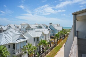 A coastal residential area with multiple houses featuring gabled roofs and a clear view of the ocean.