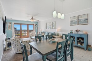 A coastal-themed living room with a dining area, large windows, and a view of the ocean. - La Mirage Condo 323 Beachfront Resort Condominiums with Private Boardwalk (Port Aransas)