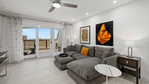 A modern living room with a grey sectional sofa, a small side table, and a ceiling fan.