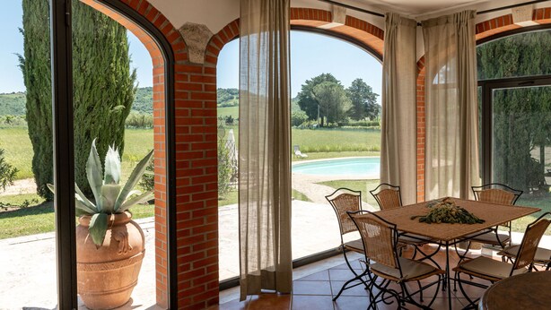 A dining area with a view of a swimming pool and greenery. - Le Cascate by Interhome (Saturnia)