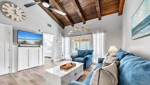 A modern living room with a wooden ceiling, a large TV, a sofa, and a coffee table. - Pet Friendly! Private Beach Access! Chateau La Mer 8C Destin! (Destin)