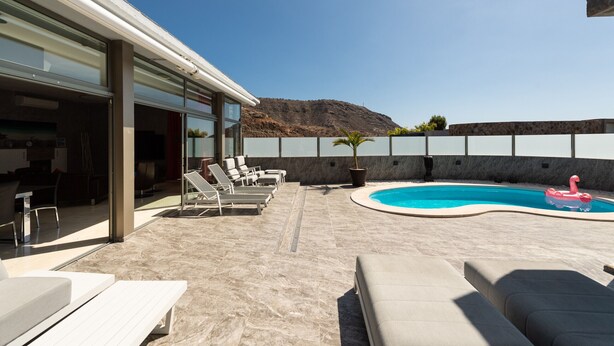 A rooftop pool area with lounge chairs, a swimming pool, and a mountain view. - Spectacular house with private heated pool in paradise (Mogán)