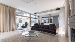 A modern living room with a glass coffee table, leather sofa, and a view of the kitchen and dining area. - Spectacular house with private heated pool in paradise (Mogán)