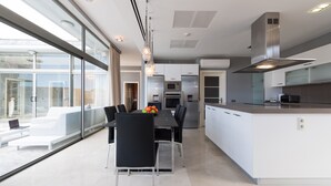A modern kitchen with a central island, built-in appliances, and large windows. - Spectacular house with private heated pool in paradise (Mogán)